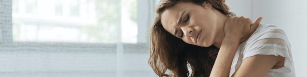 moody young woman holding her neck